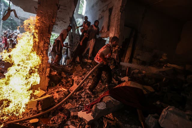 <p>Civilians and firefighters try to put out a fire caused by an Israeli army attack in Gaza</p>