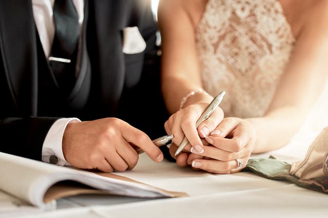 Couple signing wedding certificate, marriage registration and document paper